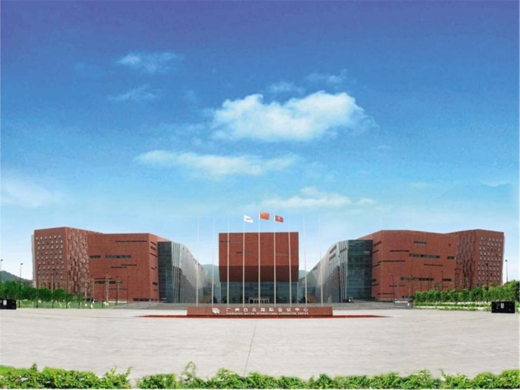 Guangzhou Baiyun International Convention Center في قوانغتشو: مبنى كبير مع وجود علامتين أمامه