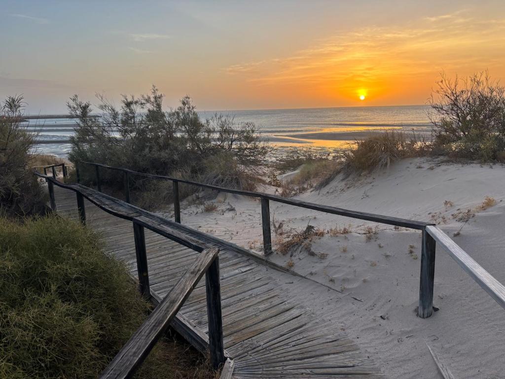 a wooden staircase leading to the beach with the sunset at Sunrise Beach Hideaway in Exmouth