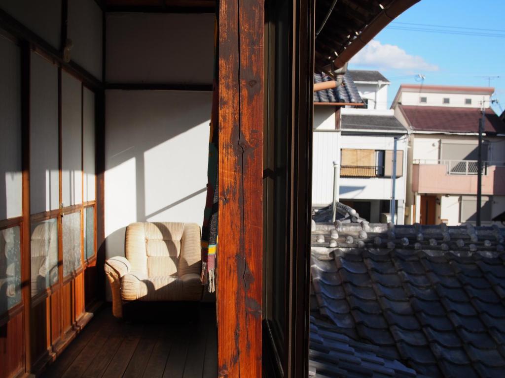 a balcony with a chair on a building with a window at The Asagiri Guest House in Tanabe