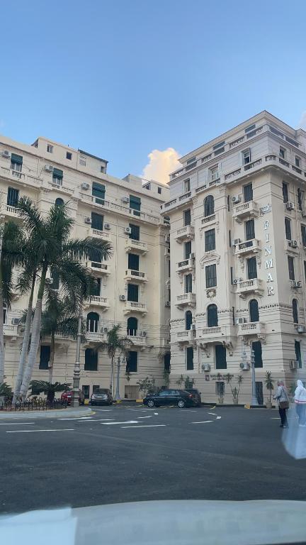 a large white building with palm trees in front of it at Graeco-Roman Residence-Delilah in Alexandria