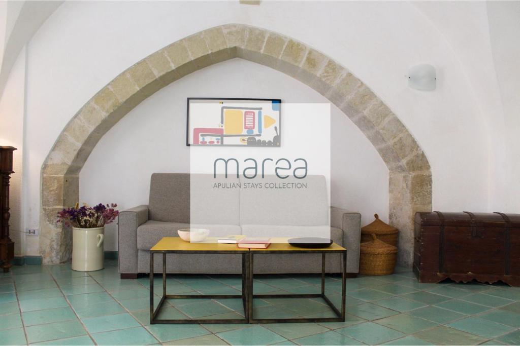 an archway with a table in front of a couch at Casa Maricla - Authentic Salento Stone House near the Sea in Otranto Old Town - Marea Stays Collection in Otranto