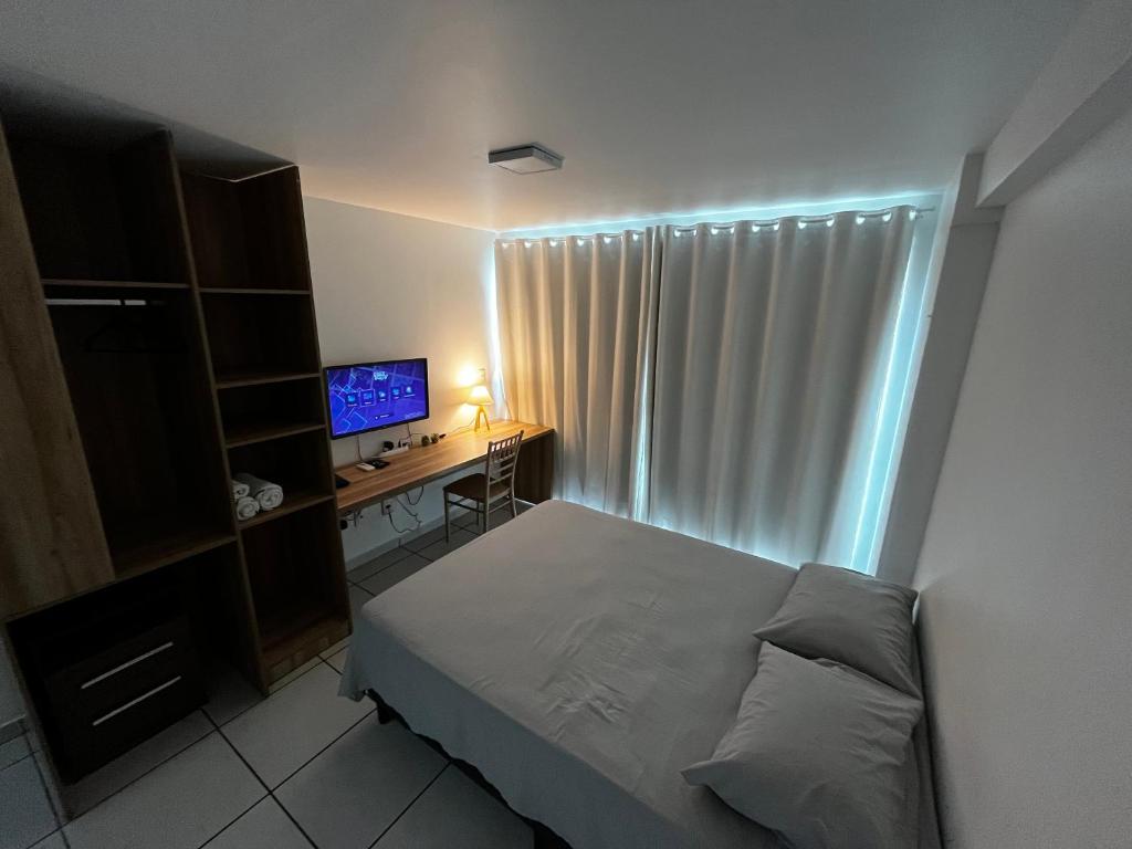 a bedroom with a bed and a desk with a computer at Studio Easy West Flat in Mossoró
