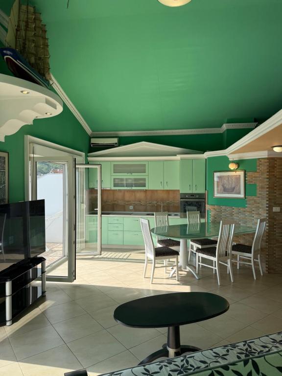 a green kitchen with a table and chairs at Apartments Nikitenko Meljine in Meljine