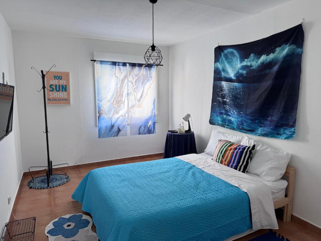 a bedroom with a blue bed and a painting on the wall at Traditional Peniche House in Peniche