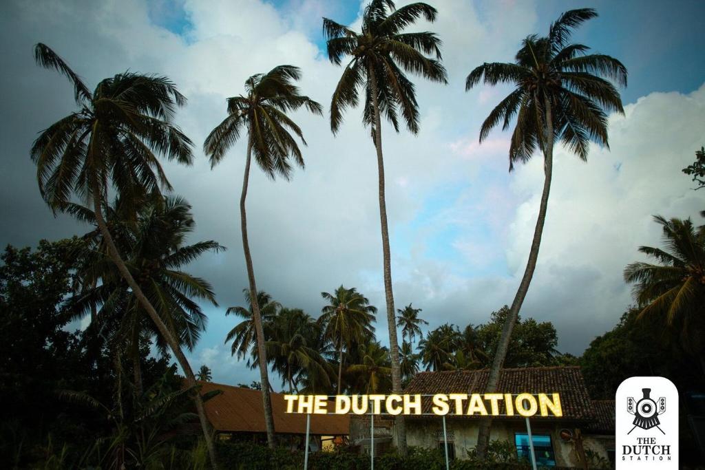 a group of palm trees in front of a sign at The Dutch Station Hotel in Ambalangoda