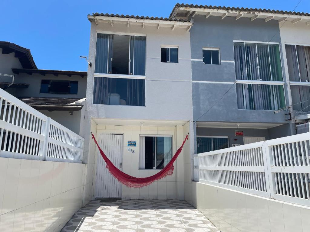 a white building with a red hammock in front of it at Ares de Salinas - 100 metros da praia in Cidreira