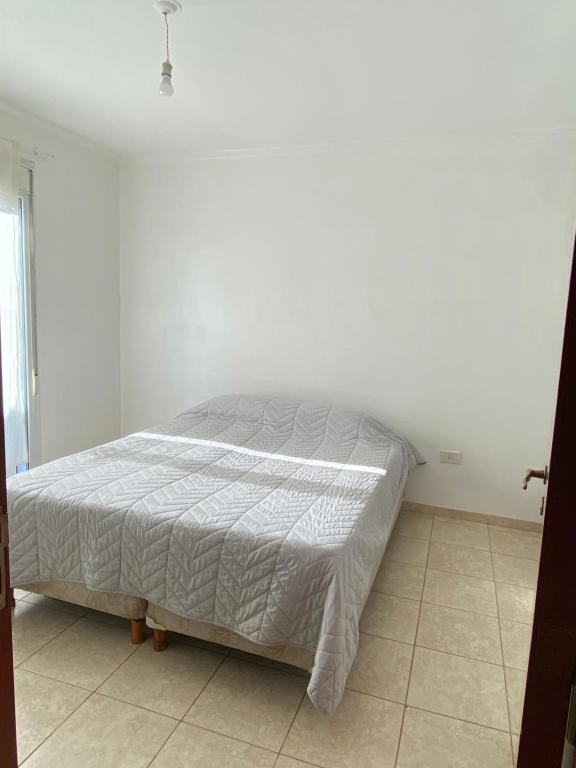 a bed in a bedroom with a white wall at Departamento zona centro in Villa María