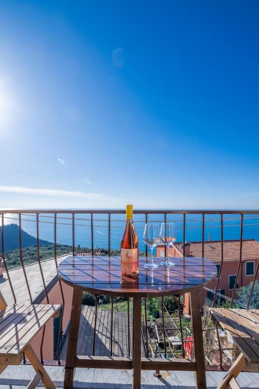 a table with two wine glasses on a balcony at Creuza de Cinque Terre Apartment in Volastra
