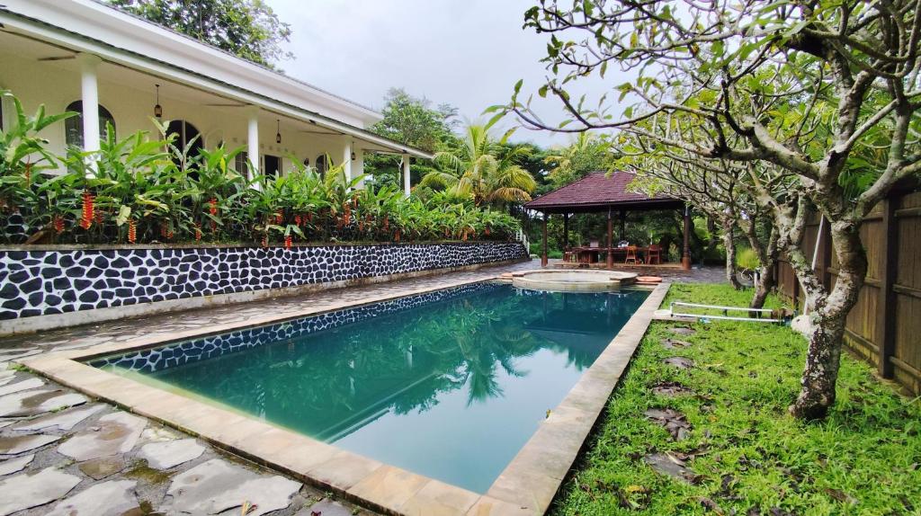 a swimming pool in a yard next to a house at YSR Himalaya Resort in Mantaak