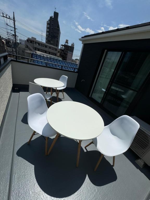 two white tables and chairs on a balcony at HB Home TOKYO in Tokyo