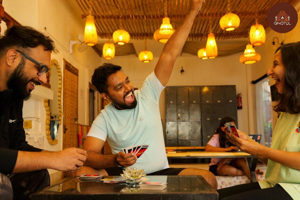 a group of people sitting around a table with their hand in the air at Ghotul Hostel & Homestay in Guwahati