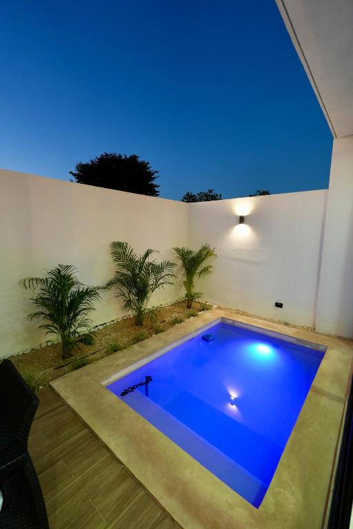 a large blue swimming pool in a backyard with palm trees at Casa Morrocoy con alberca privada y 3 habitaciones in Cholul