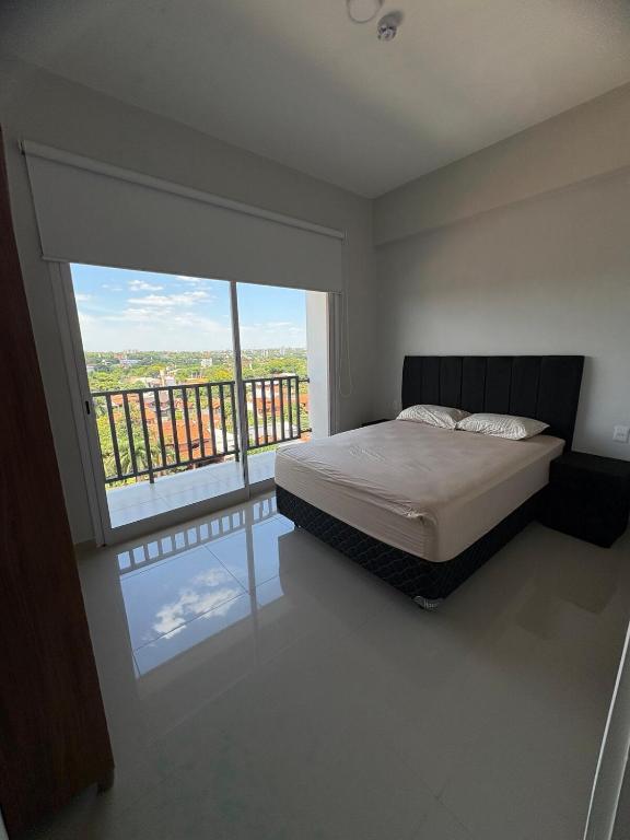 a bedroom with a bed and a large window at Departamento 1 dormitorio con piscina in Fernando de la Mora