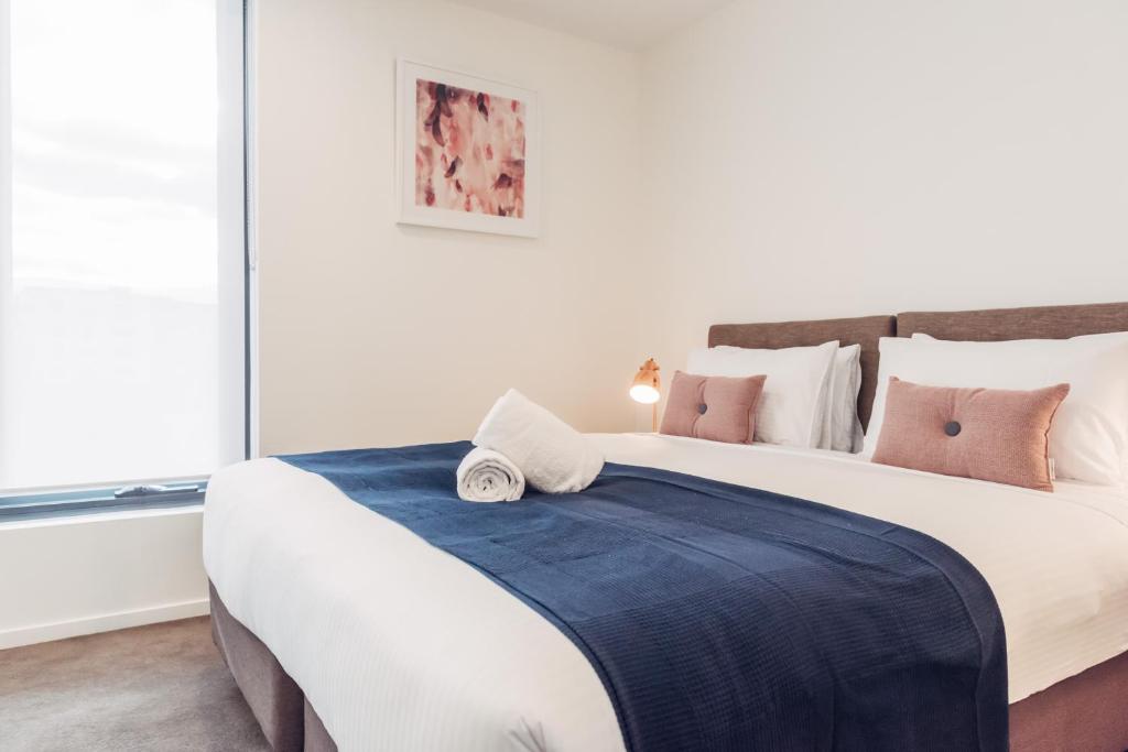 a bedroom with a large bed with pink and blue sheets at City Edge Box Hill Apartment Hotel in Box Hill