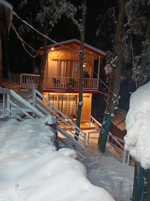 a log cabin in the snow at night at TTN - The Trekker's Nest in Joshīmath