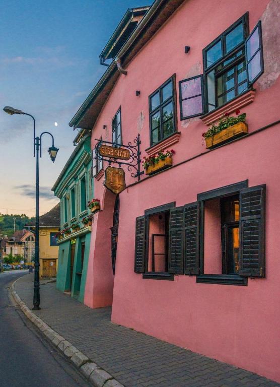 a pink building on the side of a street at Casa Savri in Sighişoara