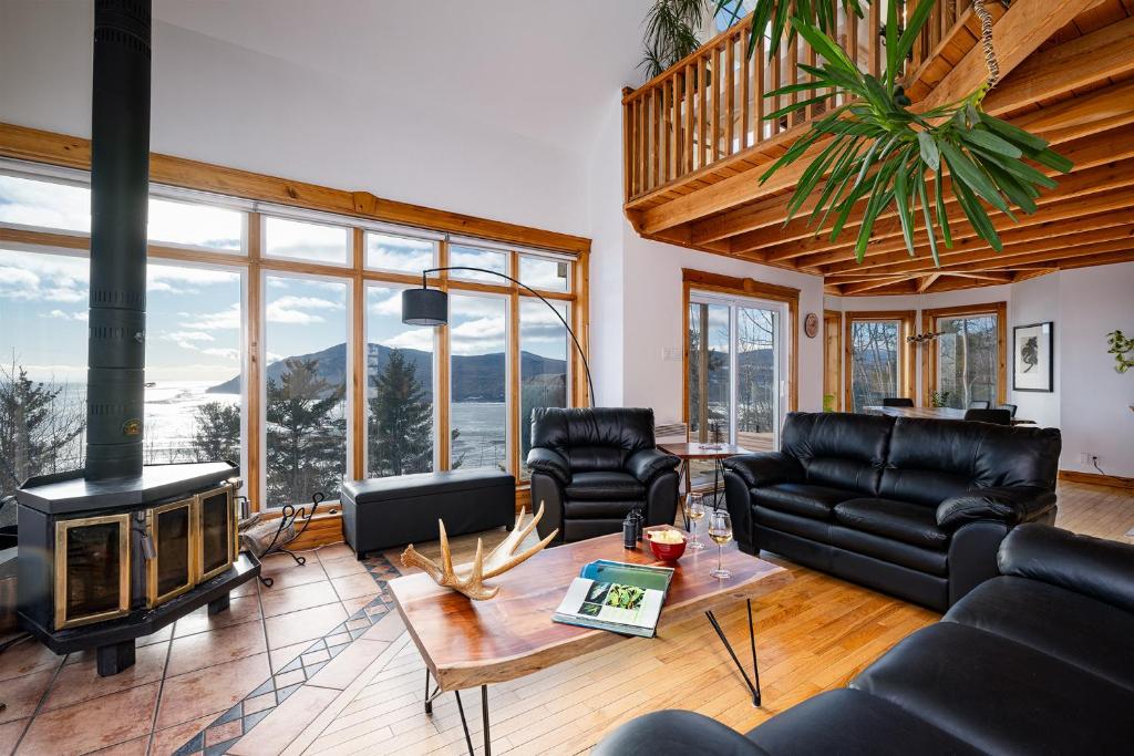 a living room with black leather furniture and a fireplace at Havre sur la Baie in Baie-Saint-Paul