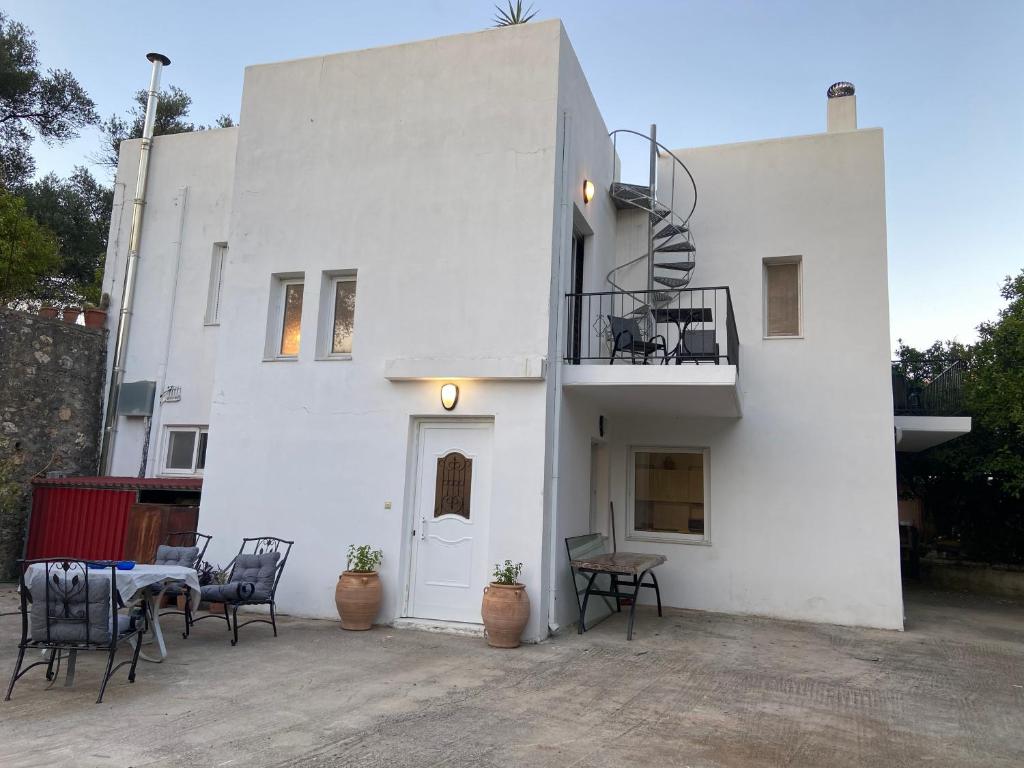 a white house with a table and chairs in front of it at Ellie's Kantanos in Kántanos