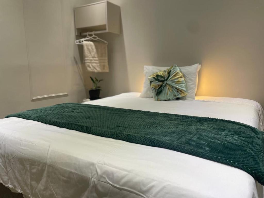 a bed with a green blanket on top of it at Refúgio Vida & Brisa in Pelotas
