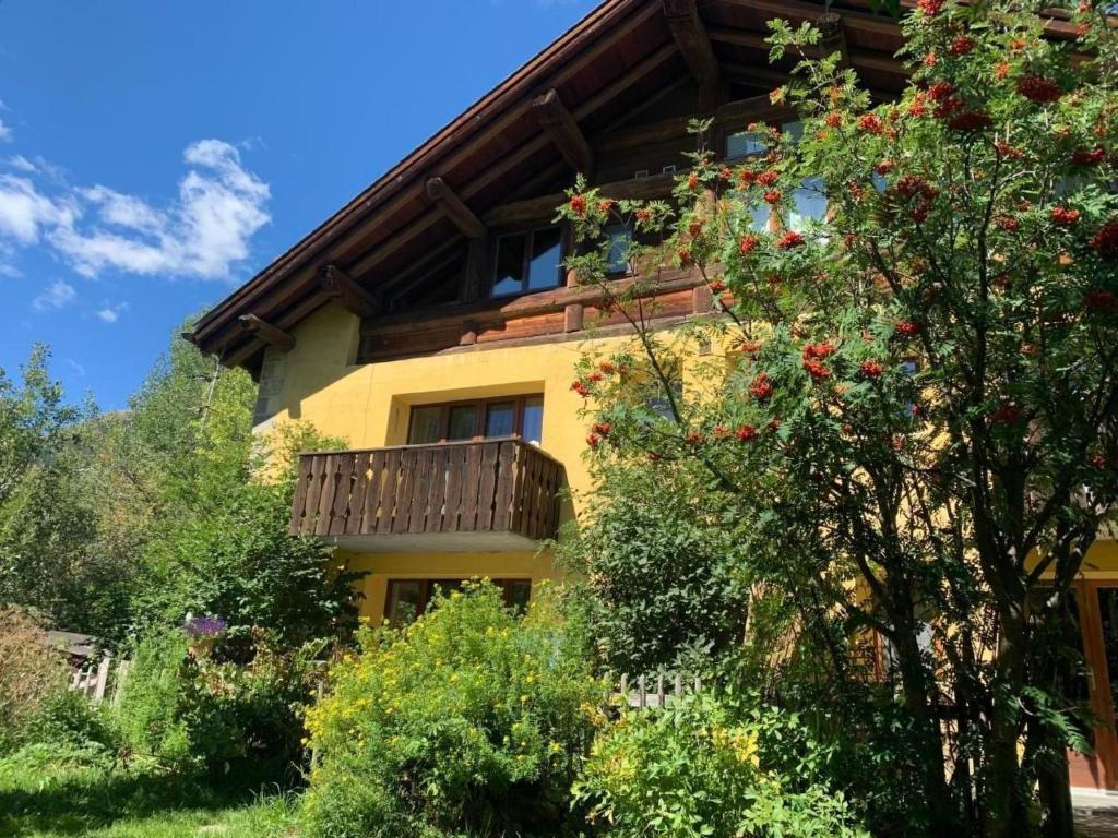 a yellow house with a balcony and trees at Apartment Wohnung Grün by Interhome in La Punt-Chamues-ch