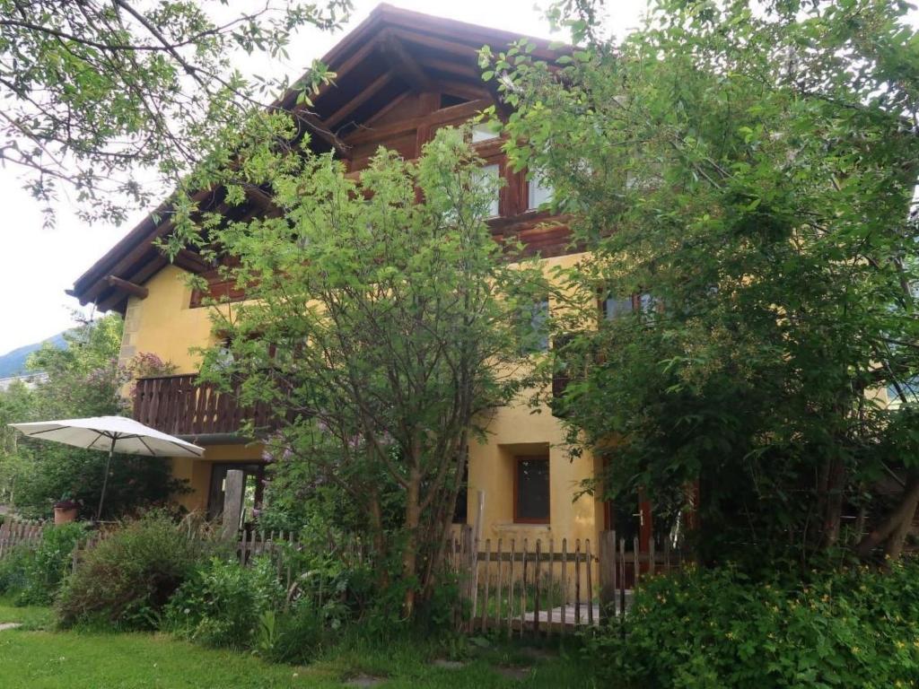 a yellow house with a fence and trees at Apartment Chesa Engel by Interhome in La Punt-Chamues-ch