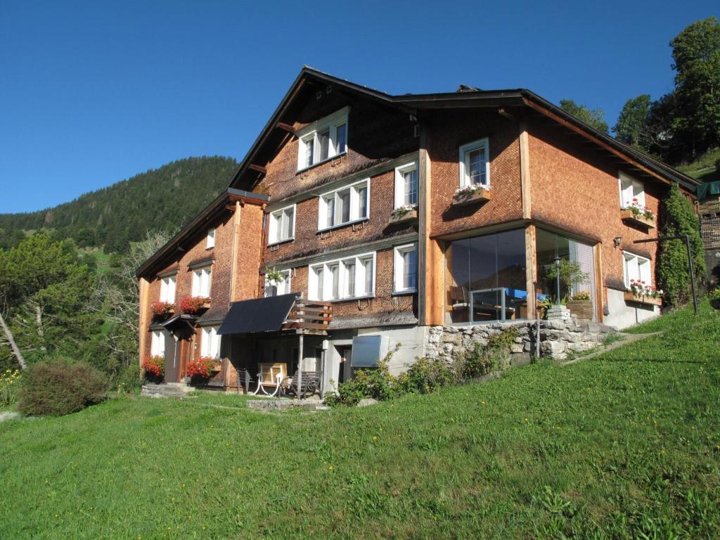 a large brick house on a hill with a green field at Apartment Gubel by Interhome in Alt Sankt Johann