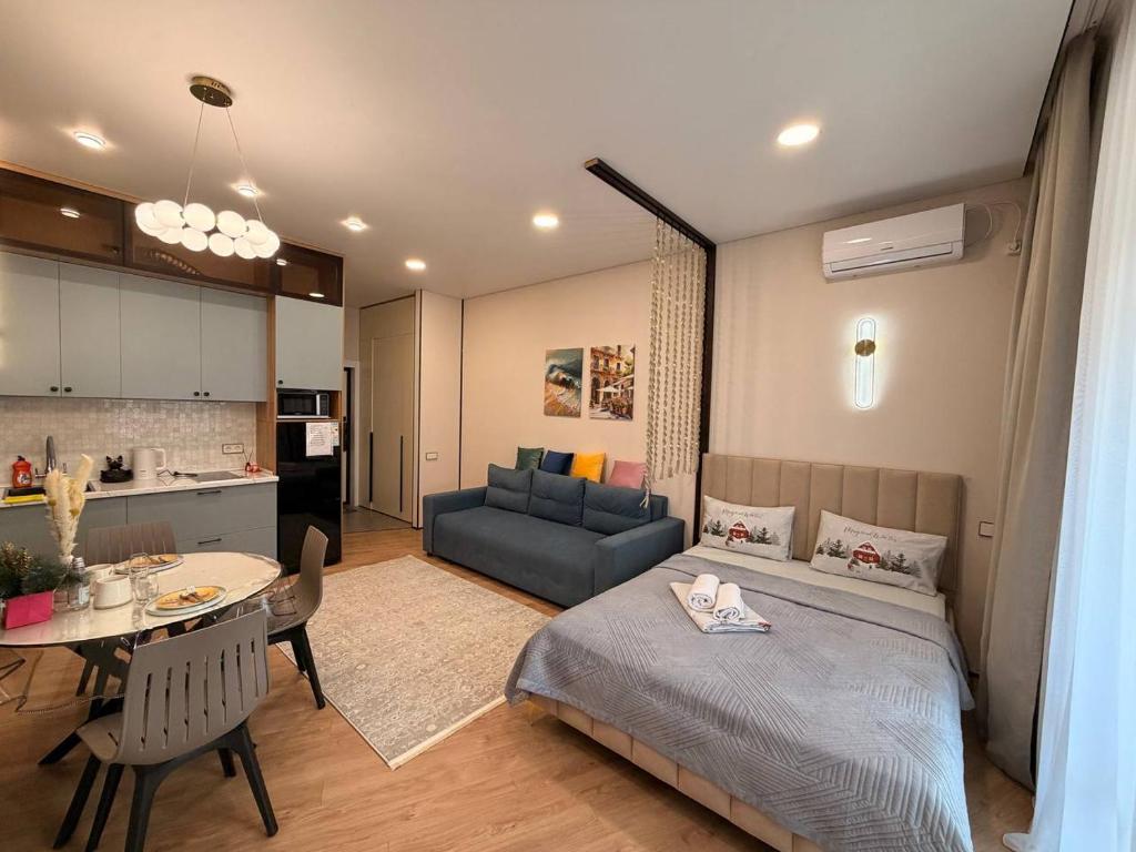a bedroom with a bed and a table and a kitchen at ЖК Tandau 399 in Almaty