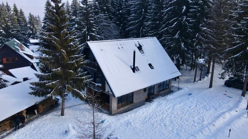a building with a clock on the roof in the snow at Cabana Bradul Adelinei in Bucsin