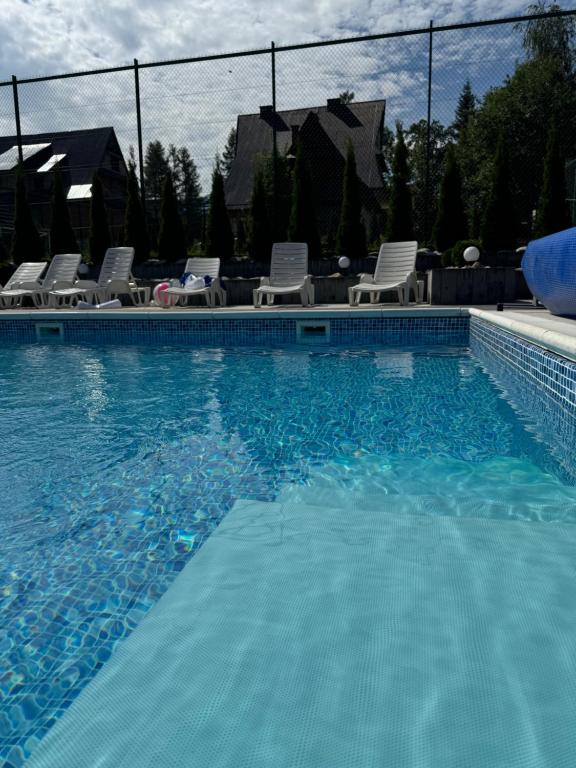 a swimming pool with chairs and a swimming pool at Koperkowe Domki Zakopane in Zakopane