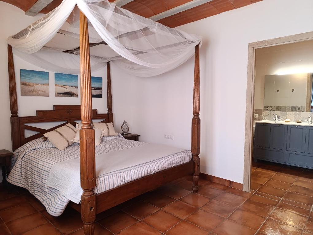 a bedroom with a canopy bed and a bathroom at Masía Can Janàs in Lliçà d'Amunt