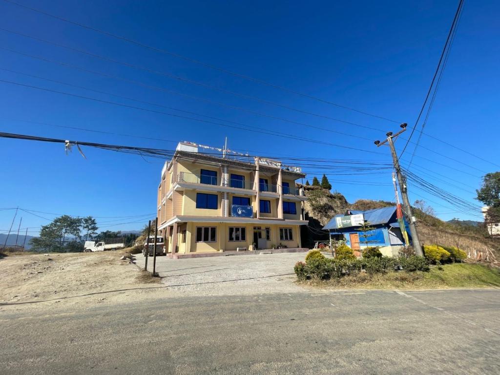a yellow building on the side of a road at Yolmo Hotel in Gorkhe