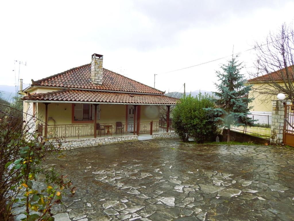 a house with a stone driveway in front of it at Menelais Guesthouse in Khotoússa