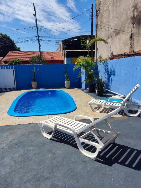 a pair of lounge chairs and a swimming pool at Casa com piscina Ana Eliza in Cambé