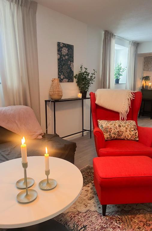 a living room with a red chair and two candles at Skolmästarevägen Åldersgräns 30 in Falun