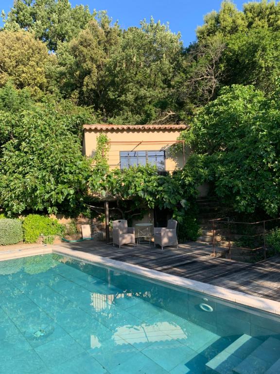a swimming pool with two chairs and a house at Les Vergers des Maures in La Garde-Freinet