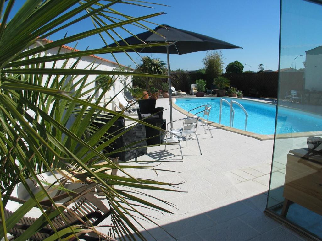 vistas a una piscina con sillas y sombrilla en Chambres d'Hôtes Le Logis du Port Paradis, en Nieulle-sur-Seudre