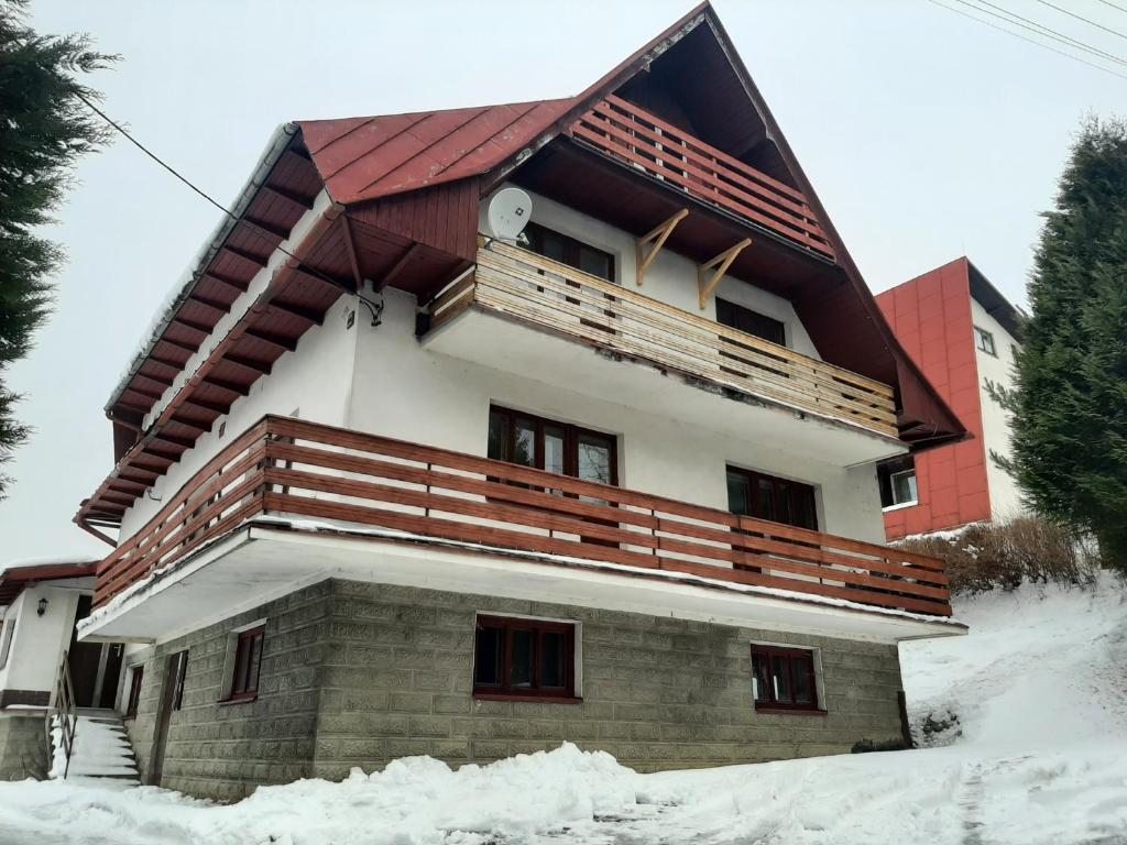 a house with a balcony on top of it in the snow at Apartament 12 in Zwardoń