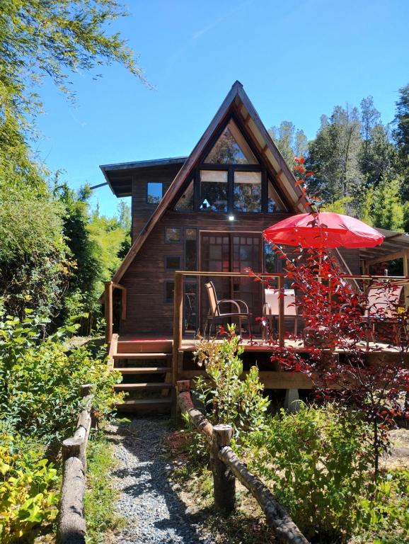 a log cabin with a red umbrella and a porch at Mini cabaña in Pucón