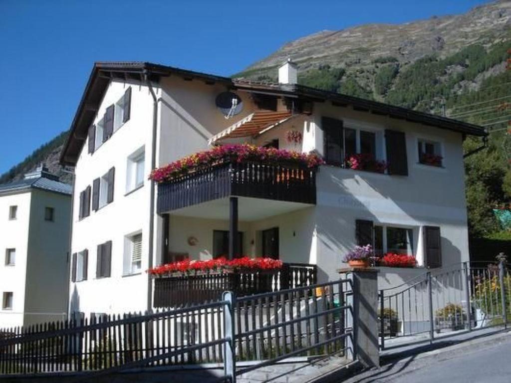 a white house with flower boxes and a fence at Apartment Chasura by Interhome in Pontresina
