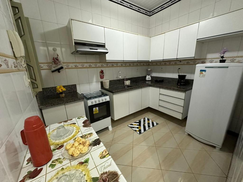 a kitchen with white cabinets and a white refrigerator at Casa aconchegante em Barra dos Coqueiros in Barra dos Coqueiros