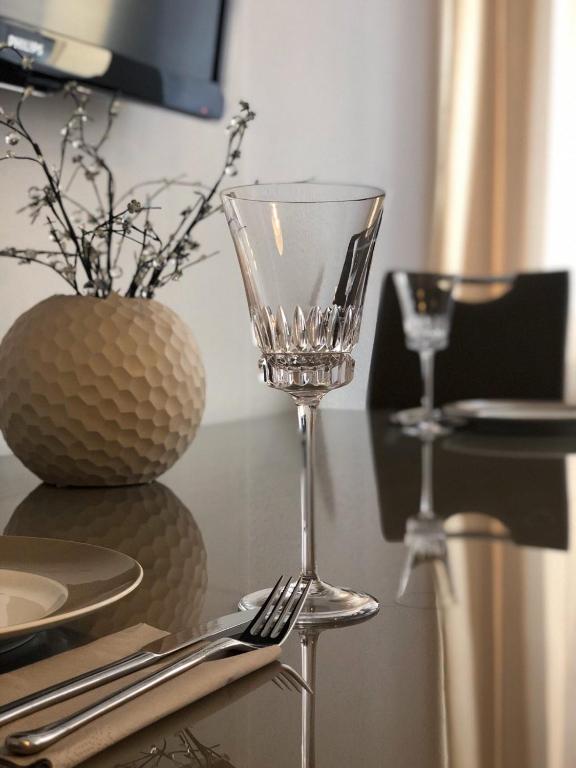 a wine glass sitting on a table next to a vase at Metropolitan Stay in Düsseldorf