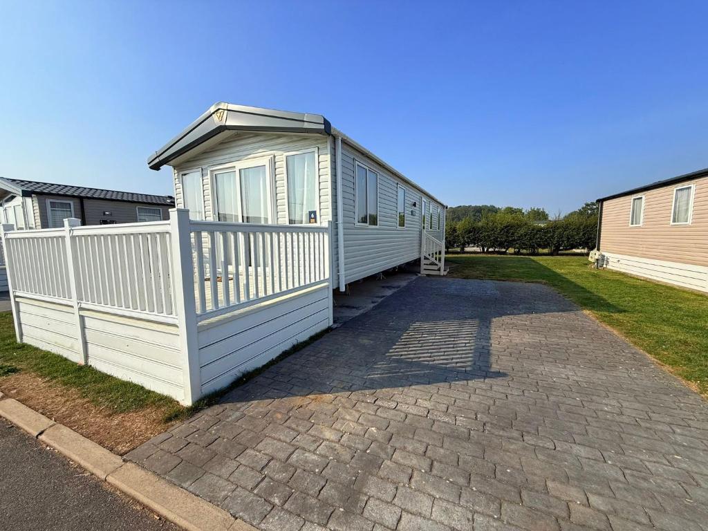 a white house with a fence on a driveway at Parkside Retreats in Kirby Misperton
