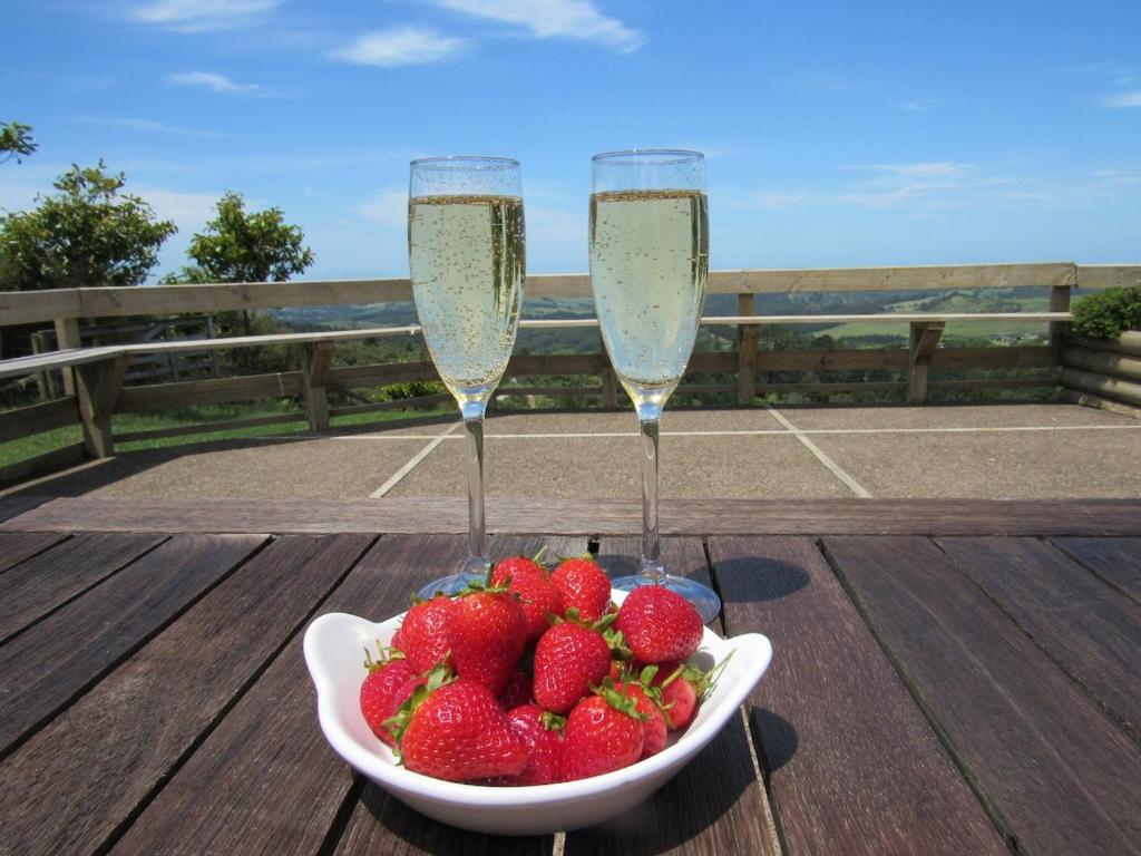 two champagne glasses and a bowl of strawberries on a table at Pine Holt Cottage in Warkworth