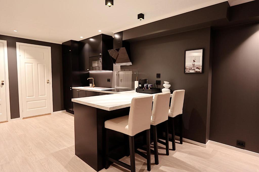 a kitchen with black walls and a bar with white chairs at Arctic City Suites 1 in Kirkenes