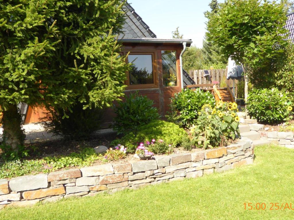a garden with a stone retaining wall and a house at Holiday Home Eifelwaldhäuschen by Interhome in Blankenheim