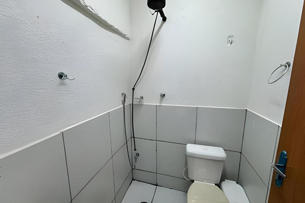 a white bathroom with a toilet and a shower at Casa Simples e Funcional em Araxá in Araxá