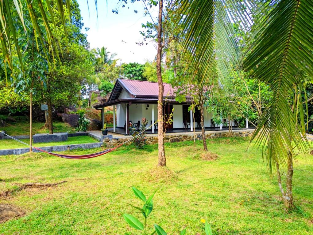 a house with a hammock in front of a yard at Dhunhill Garden in Avissawella