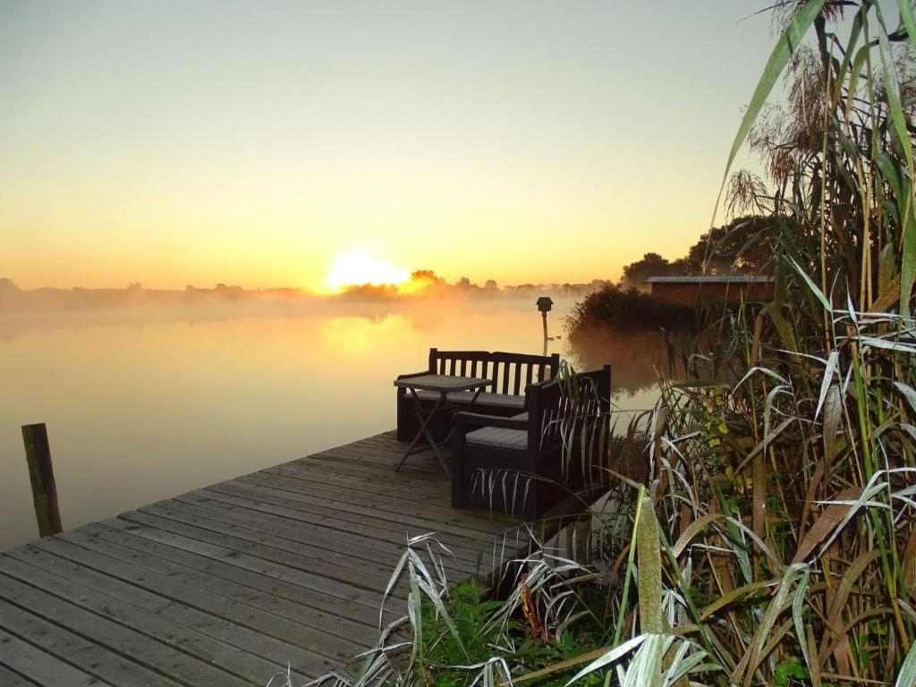 a bench on a dock with the sun setting over a lake at Apartment Wünnowblick by Interhome in Röbel