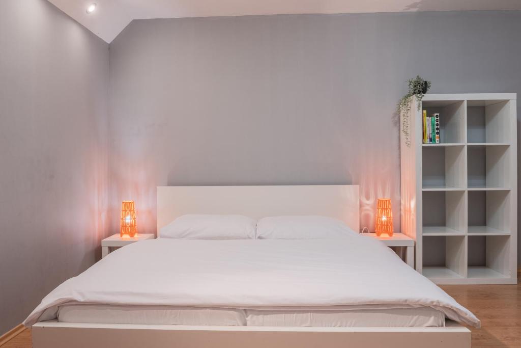 a white bedroom with a white bed and two lamps at Apartment Jursport in Závažná Poruba
