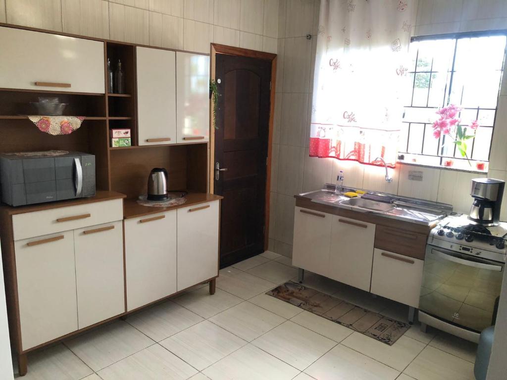 a kitchen with white cabinets and a sink and a window at Casa para diarias e empresas in Cianorte
